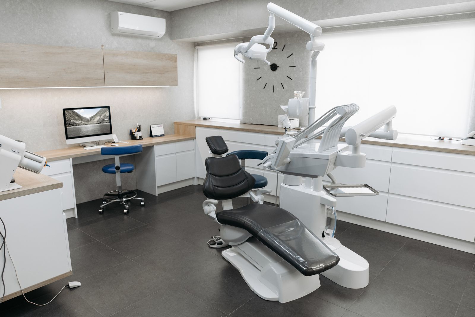 A modern dental operatory with a treatment chair and a desktop computer workstation
