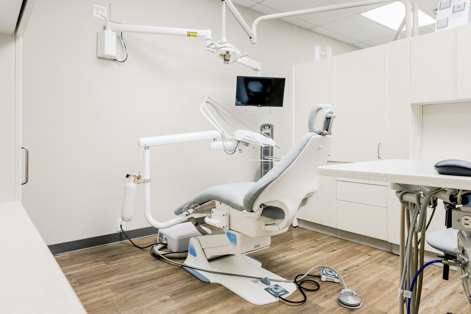 A bright dental operatory with a treatment chair and a wall-mounted monitor