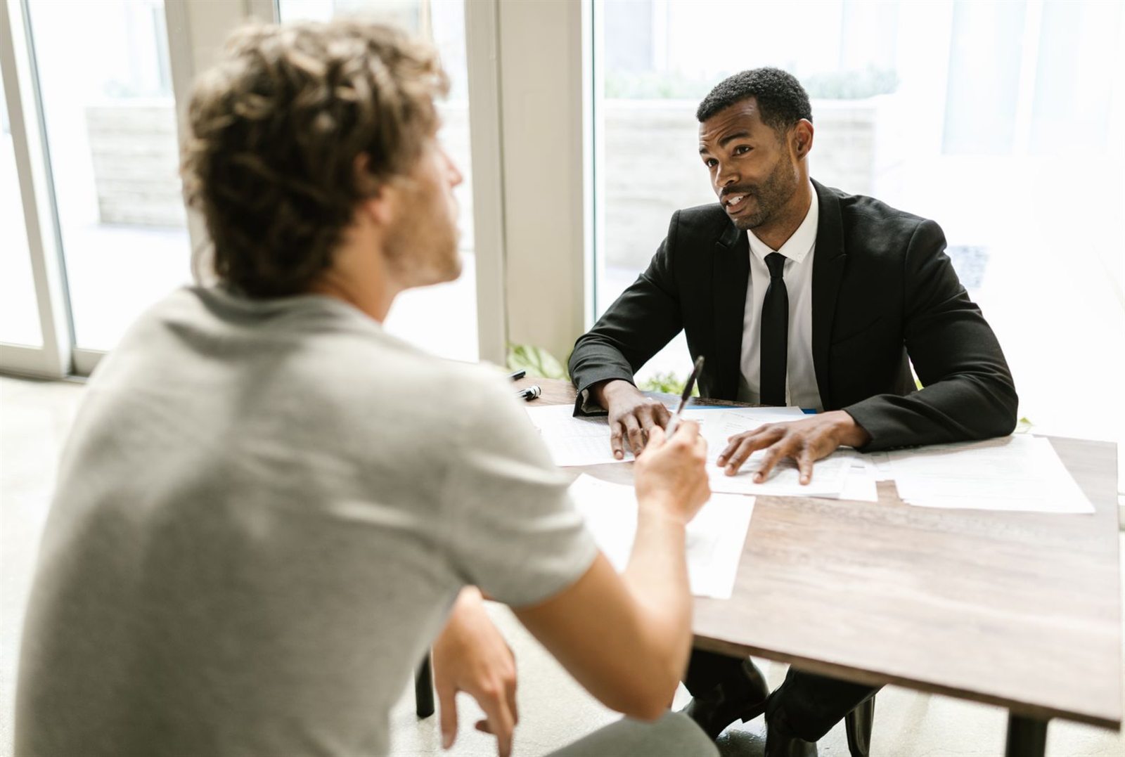 Two insurance professionals discussing paperwork together at a table in a bright, modern office
