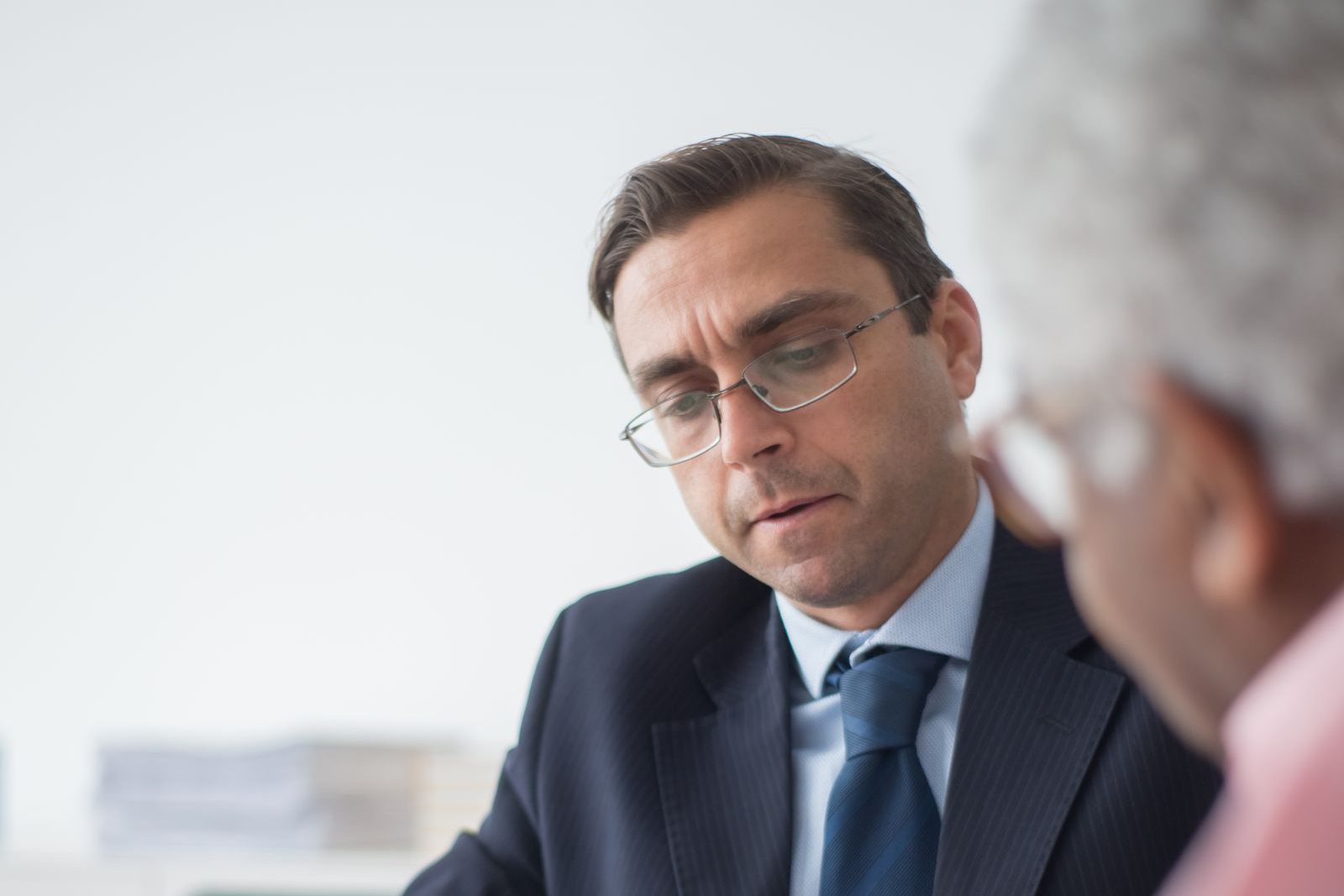 An insurance agent in glasses reviewing a document with an older client