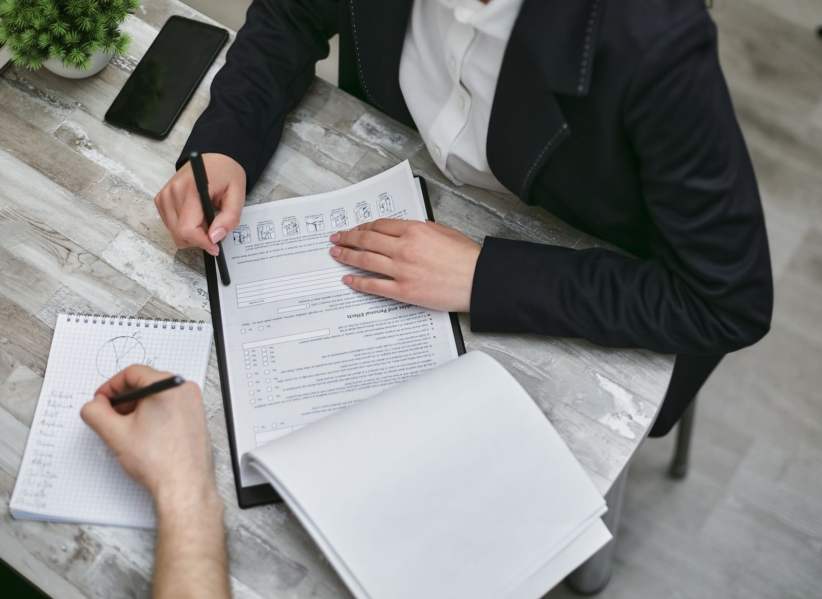 Two people reviewing and signing legal documents at a desk, seen from above