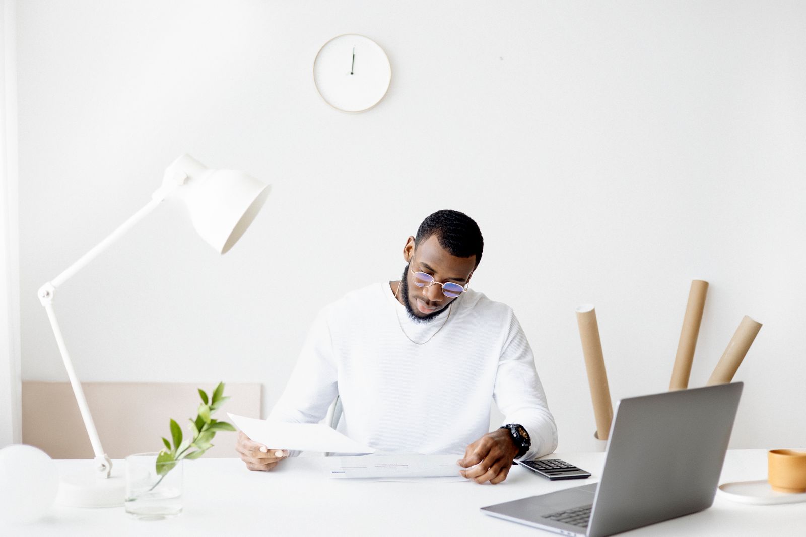 A person reviewing paperwork at a laptop in a small office